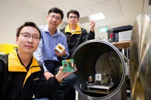 Nanyang Technological University (NTU Singapore) partners Japanese university to launch new satellite. 2 NTU Assoc Prof Low Kay Soon (centre) holding the prototype of the AOBA VELOX-III microthruster with his researchers, Tran Quang Vinh (right) holding two pieces of Teflon used as thruster fuel and Kang Bingyin (left) holding their custom-designed circuitry. To the right is the custom-built vacuum test chamber with the actual VELOX-III microthruster which will be launching to space next year. Copyright : NTU Singapore